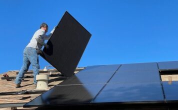 Mężczyzna montujący panele fotowoltaiczne na dachu
